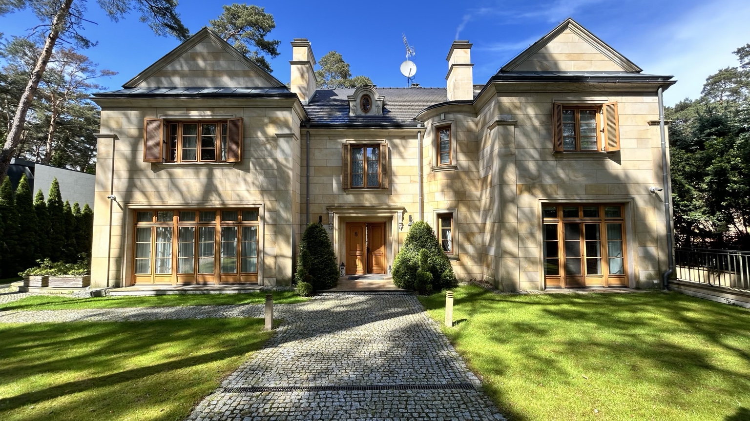 Elegant stone residence framed by trees and a landscaped garden