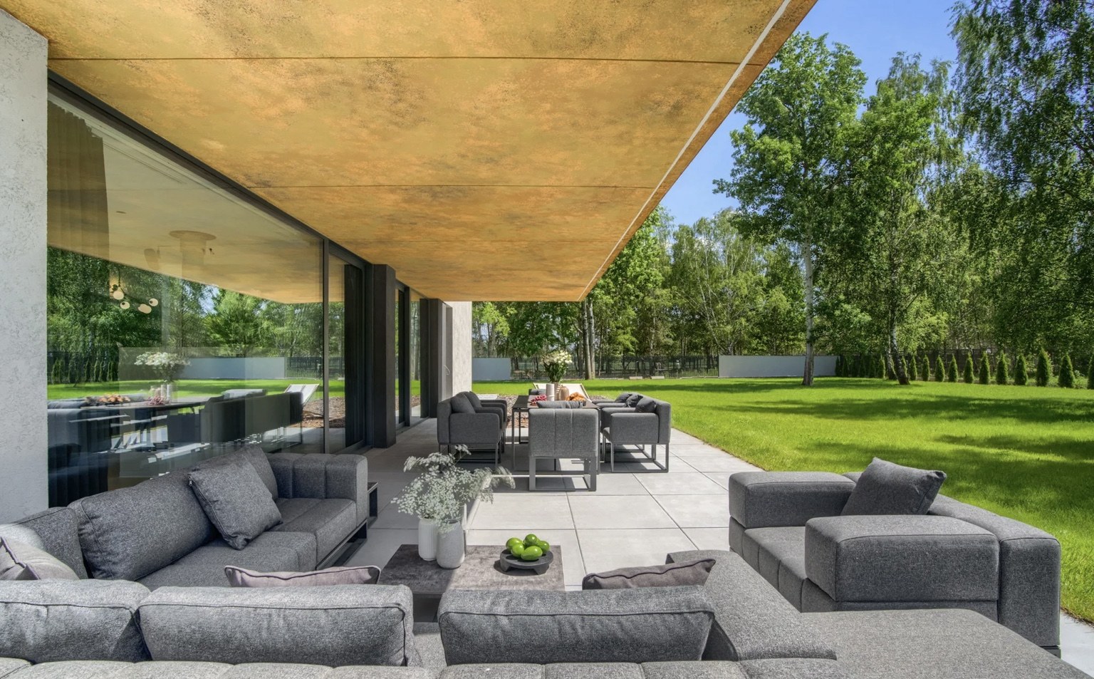 Covered residence terrace opening onto a green garden