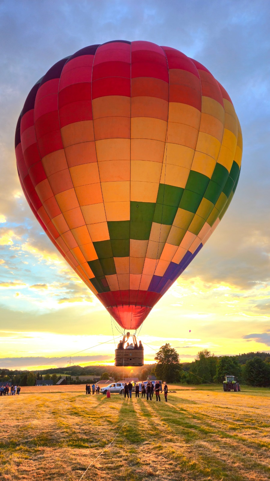 Hot air balloon at sunset above an open field
